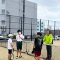 テニスの指導を受ける学生たち